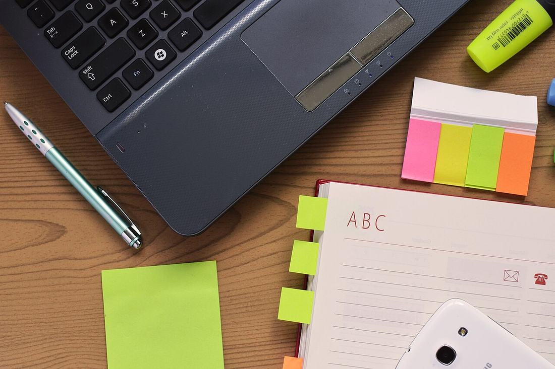 A laptop, notebook and pen on a desk