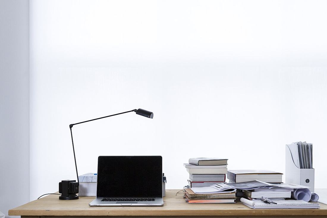 A laptop beside a stack of books